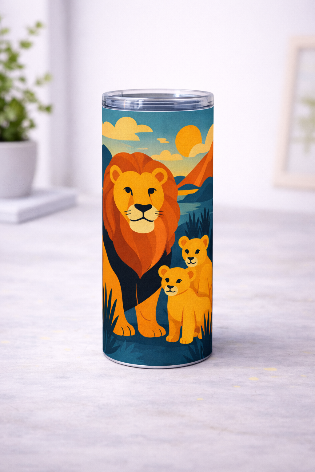 Tumbler blanc avec couvercle transparent et illustration coloree de lion et de deux lionceaux, pose de face sur une surface claire avec fond interieur flou